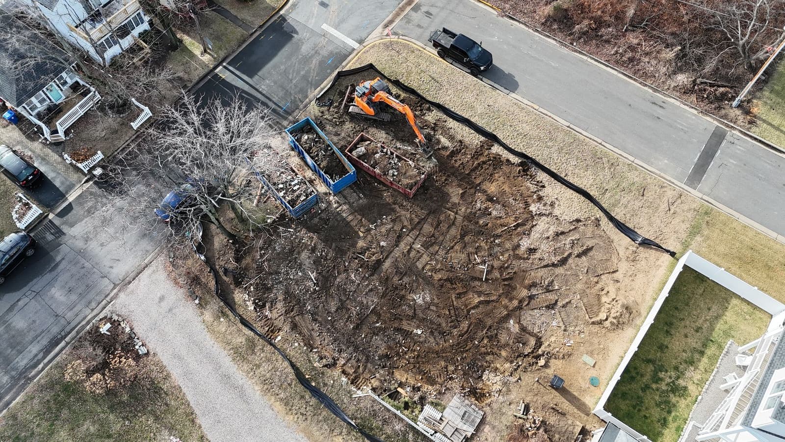 Aerial view of a residential lot after a house demolition, with debris loaded into roll-off containers.