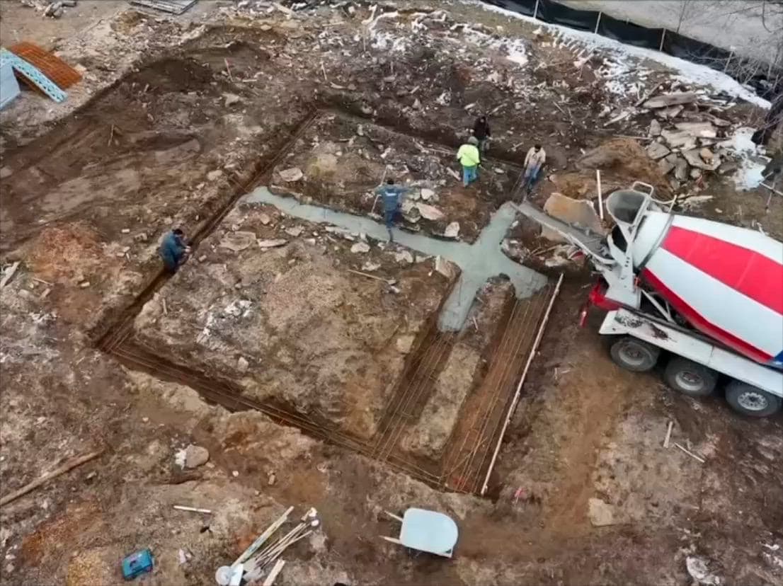 Aerial view of footings being poured into an excavated foundation outline.