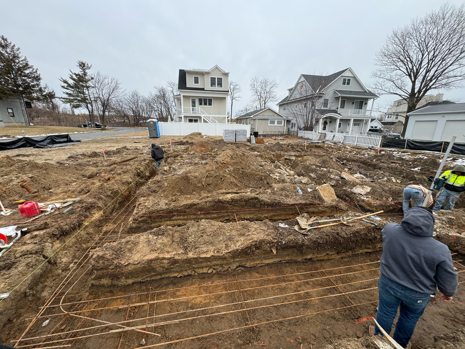 Footing trenches dug and set with rebar for a new home foundation on a residential street.
