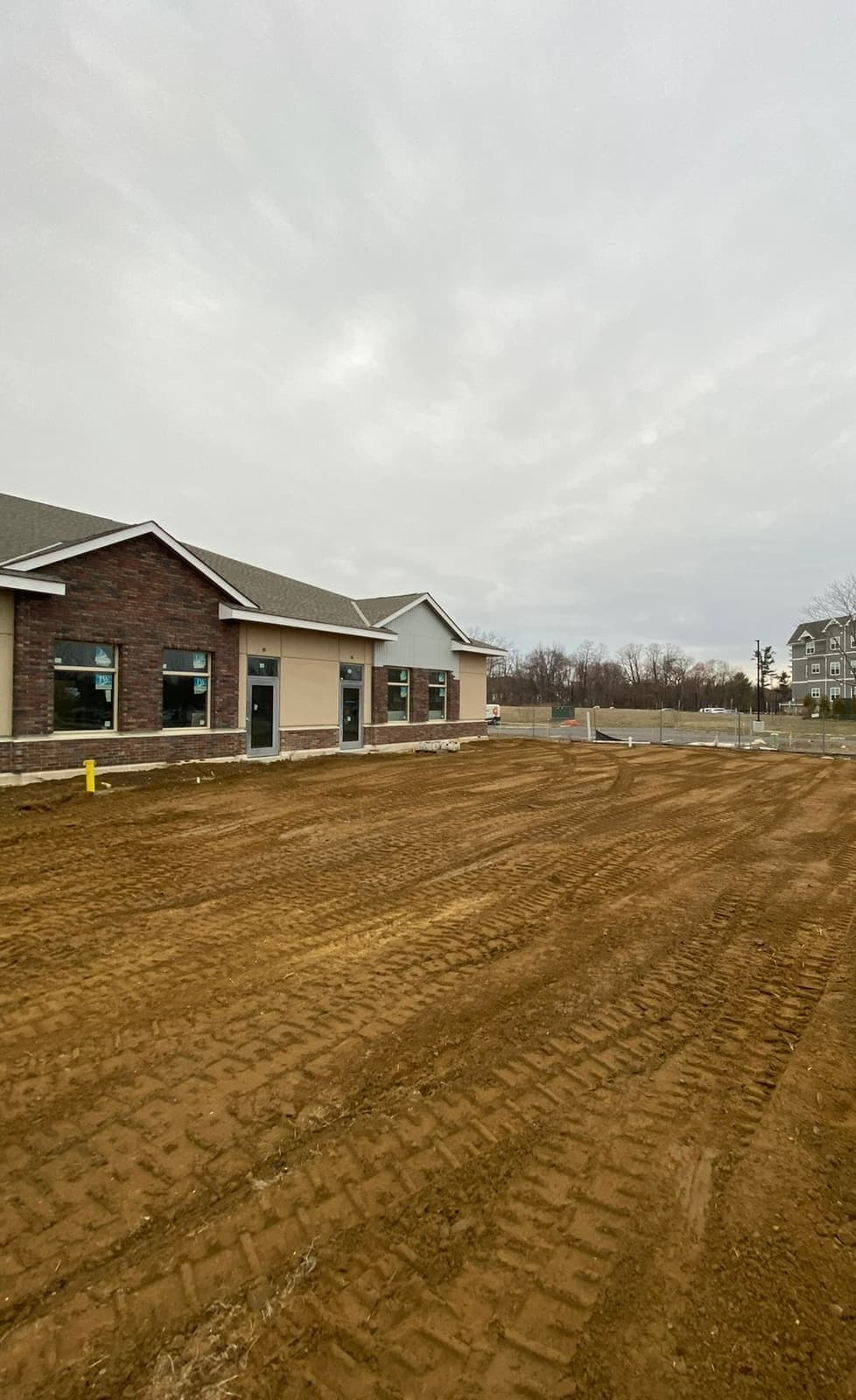 A graded building pad finished flat next to a new single-story building.