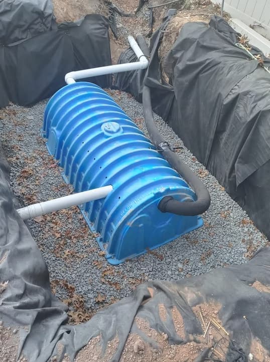 A stormwater chamber set on clean stone and wrapped in fabric, ready for backfill.